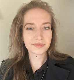 A selfie of a young woman with light brown hair and green eyes. She smiles at the camera.