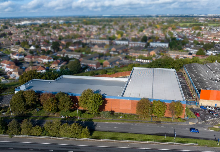 An aerial view of a building with a red metal roof and a large parking lot.